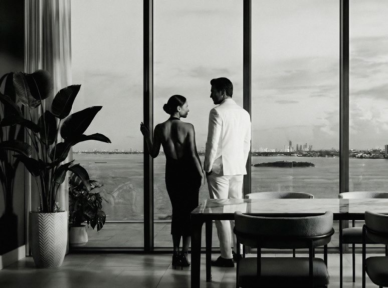 Residence interior with floor-to-ceiling impact glass onto the bay, from the approved project materials. Finishes vary by residence type.